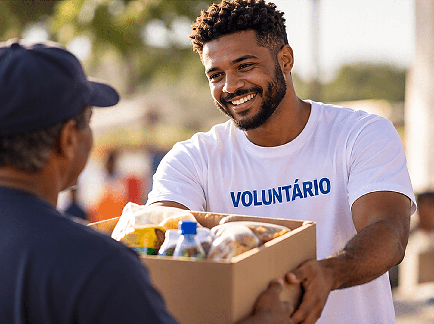 Voluntário sorrindo entrega uma cesta de alimentos